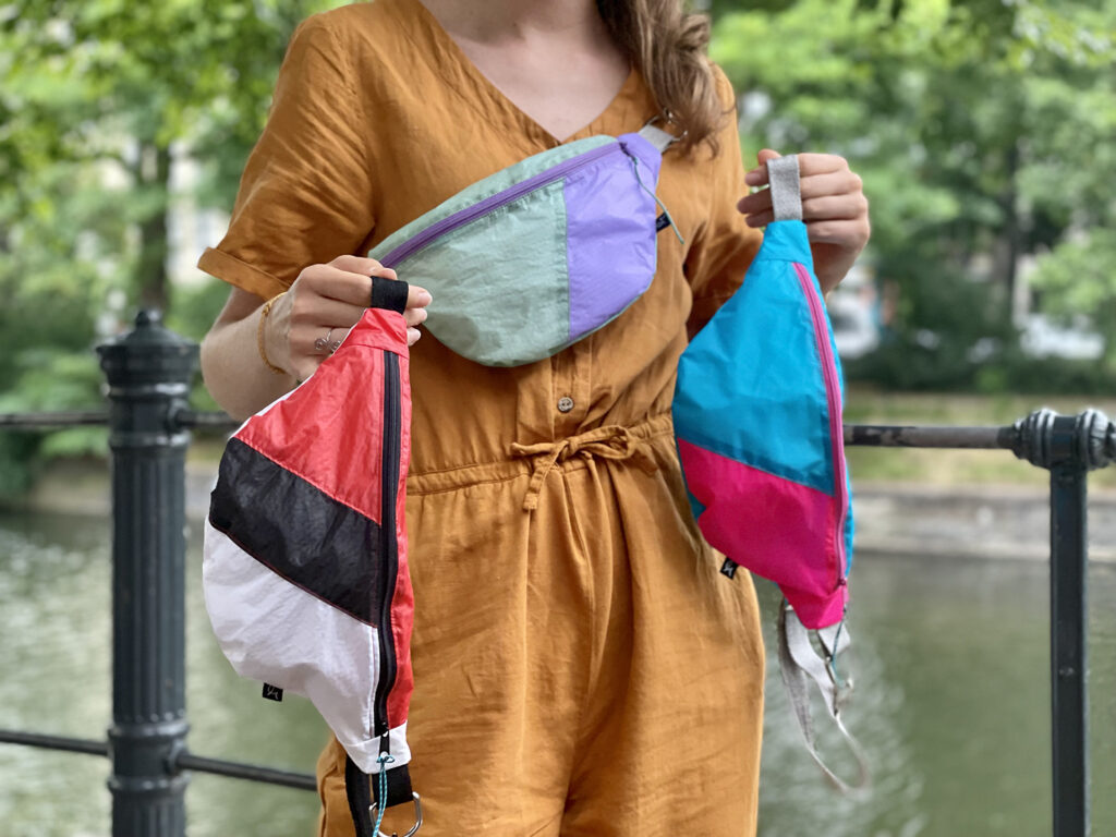 immagine di Elisa che indossa i marsupi realizzati riciclando i tessuti di parapendii e paracaduti che non volano più 