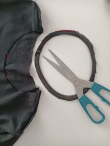 Anello di tessuto ricavato da una maglietta riciclata accanto a un paio di forbici per un progetto creativo fai da te