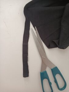 Taglio del bordo inferiore di una maglietta con le forbici per un progetto di riciclo creativo