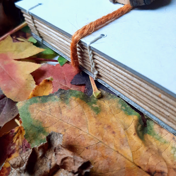 Piano di lavoro con foglie e quaderno con cucitura copta