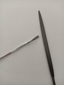 Lima e filo di alluminio utilizzati per rifinire un ciondolo in un progetto creativo fai da te