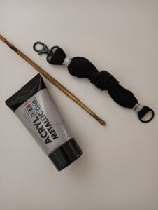 Braccialetto fai da te realizzato con tessuto riciclato durante la fase di decorazione con colore acrilico argentato