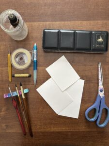 Tutto l'occorrente per realizzare un condolo di acquerello: Forbice, colori, carta, pennelli, penne scotch, indelebili
