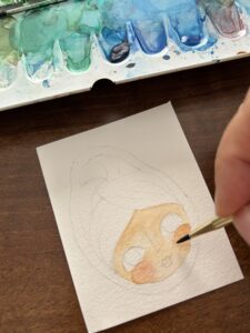 mano che colora l'acquerello da inserire nel ciondolo di carta