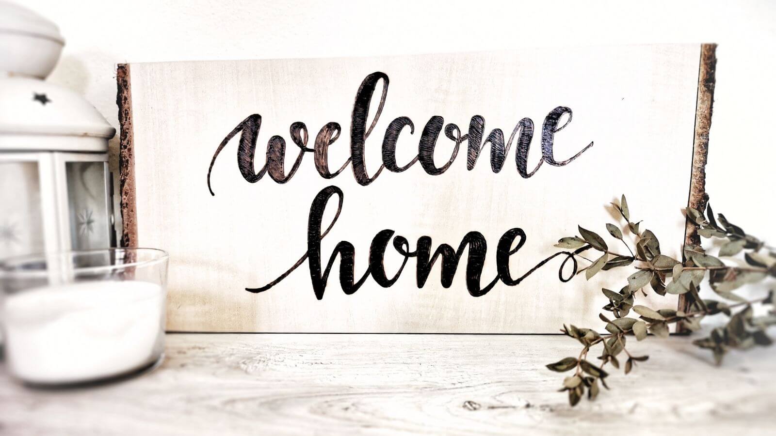 Targa di benvenuto con la scritta "Welcome home" fatta con pirografo