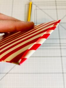 Piano da lavoro con foglio di carta da regalo a strisce bianche e rosse piegato e mano