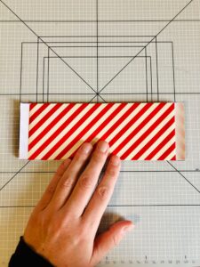 Piano da lavoro con foglio di carta da regalo a strisce bianche piegato e mano