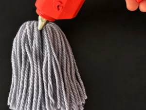Colla a caldo applicata sulla parte superiore di un fantasmino di lana azzurro