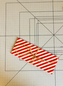 Piano da lavoro con foglio di carta da regalo a strisce bianche e rosse piegato con nastro giallo