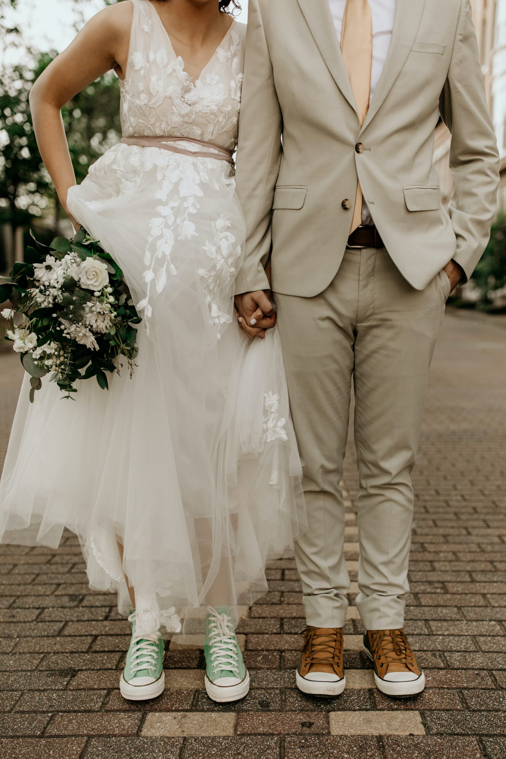 Sposa e sposo che indossano con i vestiti da cerimonia scarpe da ginnastica (Converse)