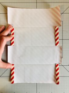 Piano da lavoro con foglio di carta da regalo a strisce bianche e rosse piegato
