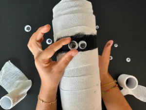 Occhietti mobili applicati alla fascia nera di una lanterna ricoperta da garza bianc a forma di mummia