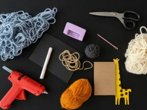 Materiali per realizzare una ghirlanda di fantasmini di lana per Halloween, colla a caldo, lana, righello, forbici