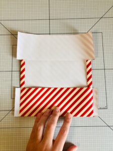 Piano da lavoro con foglio di carta da regalo a strisce bianche e rosse e mano