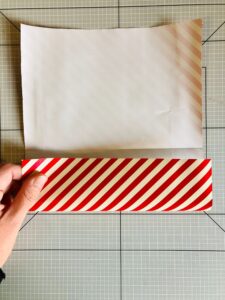 Piano da lavoro con foglio di carta da regalo a strisce bianche e rosse e mano