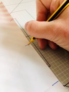 Piano da lavoro con foglio di carta e mano che disegna con penna